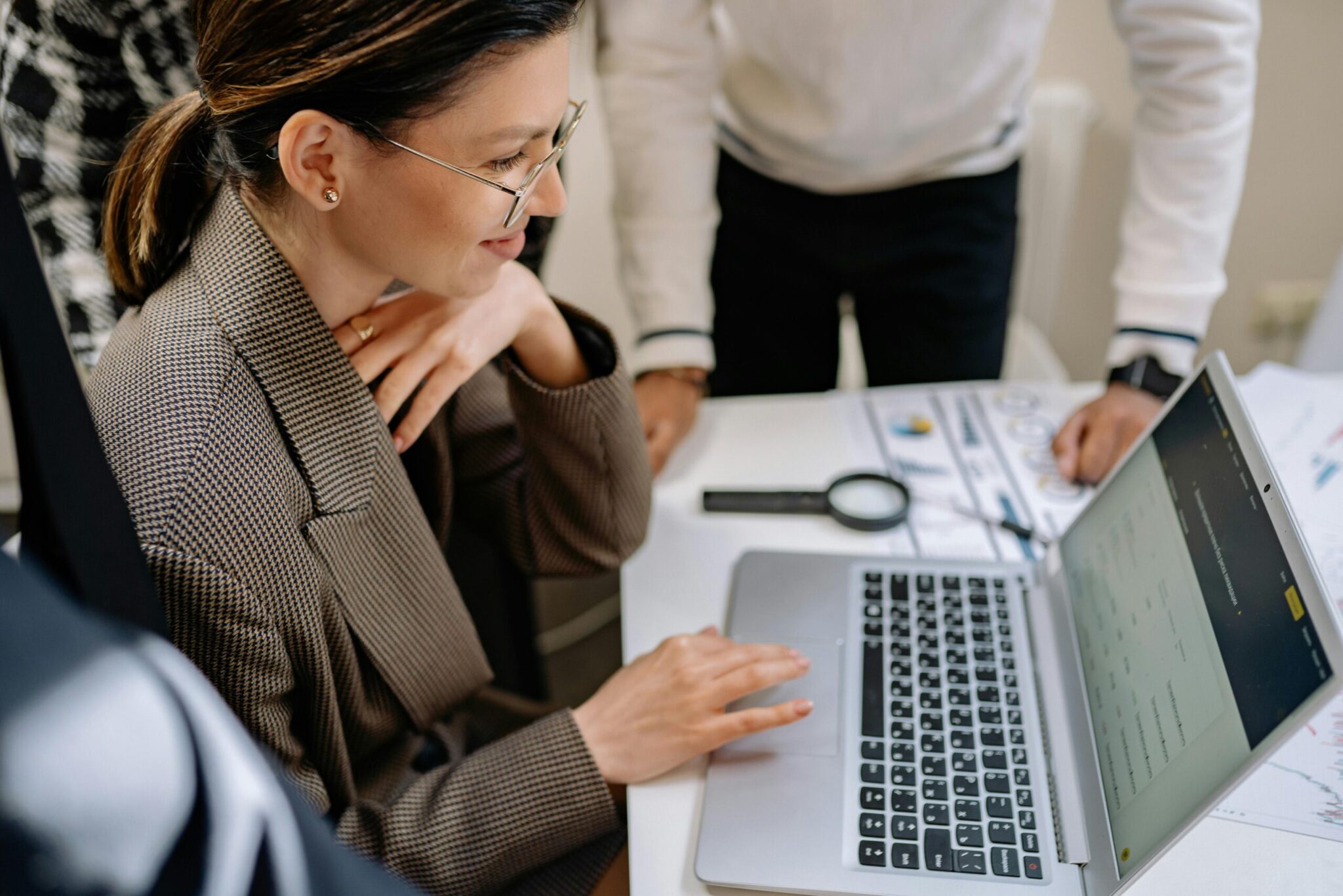Businesswoman analyzing financial data on a laptop with documents and charts on the table